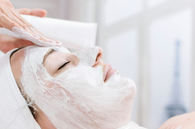 Portrait of pretty woman receiving facial massage, spa therapy for young woman receiving facial mask at beauty salon, close up